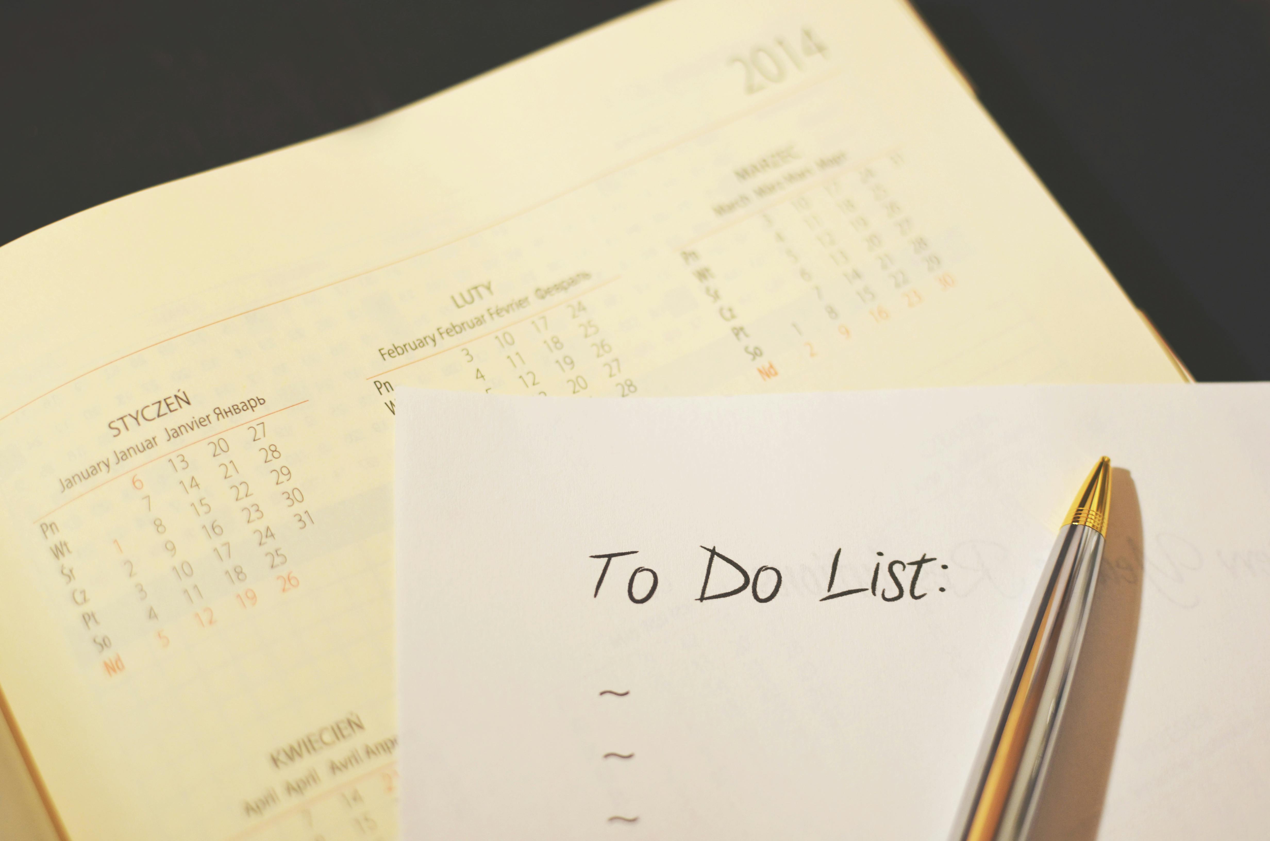 Pen on a paper calendar with a handwritten daily schedule and checklist